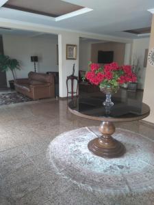 uma sala de estar com um vaso de flores sobre uma mesa em Bekassin Botucatu Hotéis Ltda em Botucatu
