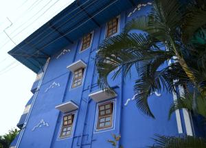 a blue building with a palm tree in front of it at Villa Theresa Beach Resort in Calangute