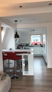 レムシャイトにあるStadtvilla Kö97 - Apartment Relaxのキッチン(白いカウンター、赤いバースツール付)