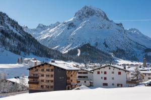 a town in the snow with a mountain in the background at Nidus Luxury Apartments in Lech am Arlberg