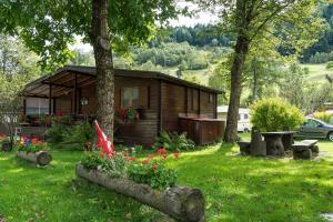 una cabaña de madera en un patio con flores en Camping Boomerang, en Poschiavo