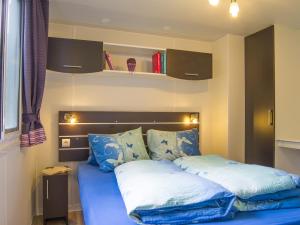 Schlafzimmer mit einem Bett mit blauer Bettwäsche in der Unterkunft Camping Boomerang in Poschiavo