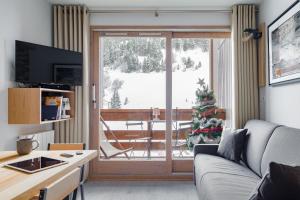 uma sala de estar com um sofá e uma árvore de Natal em RESIDENCE OLYMPIE 1 em Méribel