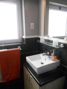 a bathroom with a white sink and two windows at Rose Lodge in Cape Town