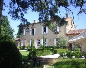 una casa grande con un patio con sillas delante en Chateau de Thegra en Balma