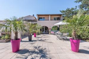 un patio con palmeras en grandes macetas rosas en Le Clos des Bruyères, en Vallon-Pont-dʼArc