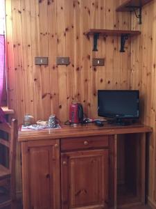 a room with a wooden wall with a desk with a television at Kleine in Gressoney-Saint-Jean