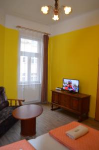 ein Wohnzimmer mit gelben Wänden und einem TV in der Unterkunft AB Apartments in Karlsbad