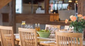 a wooden table with a bowl of flowers and wine glasses at Strand Golf in Harad