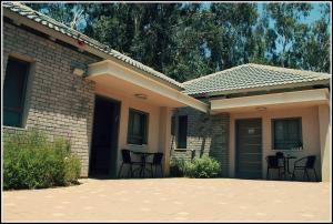 a brick house with chairs and a table in front of it at Pnina Yafa BaGalil Zimmer in Qiryat Shemona