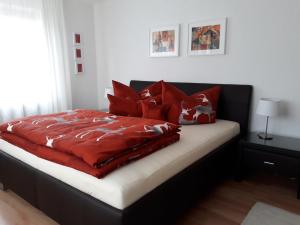 uma cama com cobertores vermelhos e almofadas em Haus Sonnenheim em Frastanz