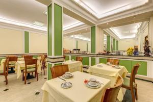 un restaurante con mesas, sillas y paredes verdes en Hotel Igea en Roma