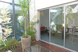 une porte coulissante en verre sur une terrasse ornée de plantes dans l'établissement Cañas Suites Urbanas, à Mina Clavero