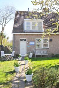 a brick house with a bench in the yard at Roosjesweg 1a in Domburg