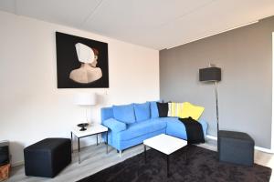 棟堡的住宿－Roosjesweg 1a，客厅配有蓝色沙发和绘画作品
