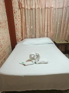 Una cama con un par de zapatillas. en Hospedaje Las Orquídeas, en Venecia