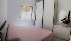 - une chambre avec un lit rose et une fenêtre dans l'établissement Appartamenti Sole a Zambrone Village, à Zambrone