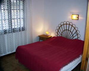 a bedroom with a red bed and a window at Casa Sol in L'Estartit
