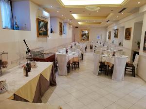 uma sala de jantar com mesas e toalhas de mesa brancas em Assisi Garden em Assis