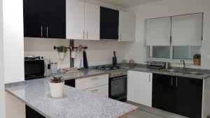 a kitchen with white cabinets and black appliances at Elegant Modern Blue Apartment in Praia