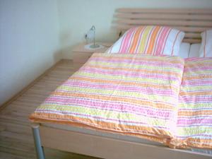 a bed with a striped blanket and a lamp on it at Ferienwohnung Am Zechenhaus in Bodenmais