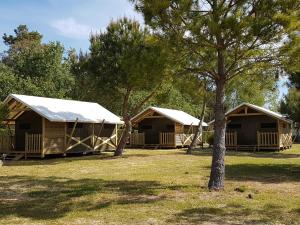 two large wooden huts in a field with trees at Camping Le Lagon Bleu in Notre-Dame-de-Monts