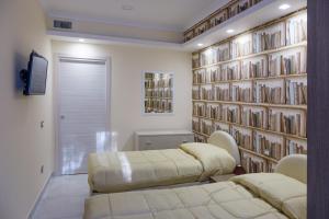 ヴィーコ・エクエンセにあるCasa Miclaのベッド2台と本の壁が備わる客室です。