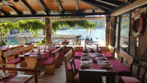 a restaurant with tables and chairs with a view of the water at Apartments Linda in Polače