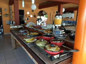 una línea de buffet con muchas ollas y sartenes de comida en Pousada Zekas, en Jacumã
