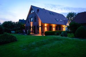 Minsen的住宿－Ferienwohnungen Hensel，绿色草坪上一座带深色屋顶的房屋