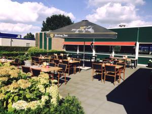 a restaurant with tables and chairs and an umbrella at Hotel de Raket in Rogat