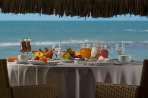 a table with fruit and juice on it with the ocean in the background at Vila Selvagem Hotel Contemporaneo in Fortim