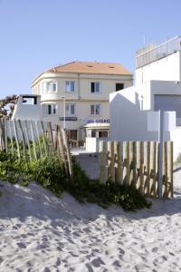 a building on the beach next to a wooden fence at Hôtel Restaurant Gédéon in Carnon-Plage