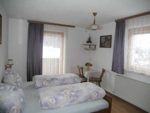 a bedroom with two beds and a table and windows at Apartments Jäger in Trins