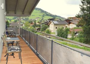 a balcony with chairs and tables and a view of a town at Flatscher‘s in Niederau