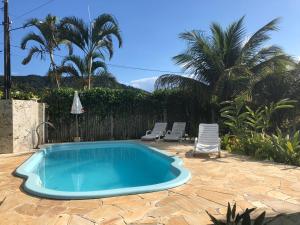 a blue swimming pool with two chairs and a fence at Pousada Farol do Marinheiro in Boicucanga