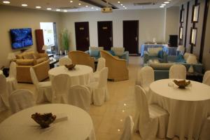 una habitación con mesas y sillas blancas y una habitación con sillas en Al Mokhmalia Residential Units en Medina