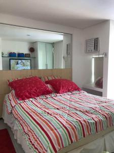 um quarto com uma cama com almofadas vermelhas e um espelho em Ancorar Flat Resort Porto de Galinhas em Porto de Galinhas