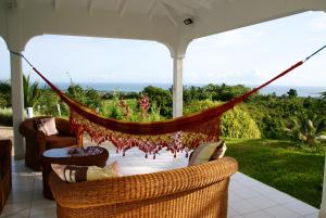 a person laying in a hammock on a porch at Horizon Karukera in Sainte-Rose