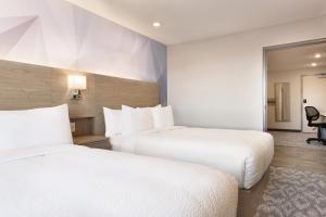 a hotel room with two beds and a mirror at Days Inn by Wyndham Calgary North Balzac in Balzac