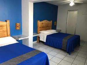 a bedroom with two beds and a blue wall at Hotel San Juan in Guadalajara