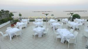 um restaurante com mesas e cadeiras brancas e água em Hotel Dolce Stella em Torre Melissa