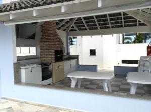 an outdoor kitchen with a table and chairs on a patio at Caraguá Martins de Sá in Caraguatatuba