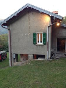 una casa con una ventana verde y un patio en Baita Mirella, en Torno