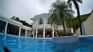 a house with a swimming pool and a palm tree at Marina's Praia Itaipu in Niterói