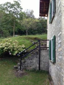 un edificio de piedra con una escalera junto a una casa en Baita Mirella, en Torno