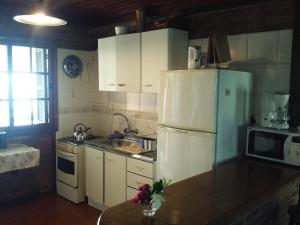 a kitchen with white cabinets and a refrigerator at El Repecho in Piriápolis