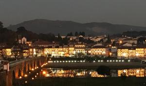 eine nachts beleuchtete Stadt mit einem Fluss und Gebäuden in der Unterkunft Arc My Otel in Ponte de Lima