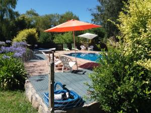 a swimming pool with an umbrella and a swimming pool at Cabañas Los Aromos in Tandil
