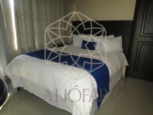una camera da letto con un grande letto e un copriletto bianco di Hotel Aljófar a Montemorelos